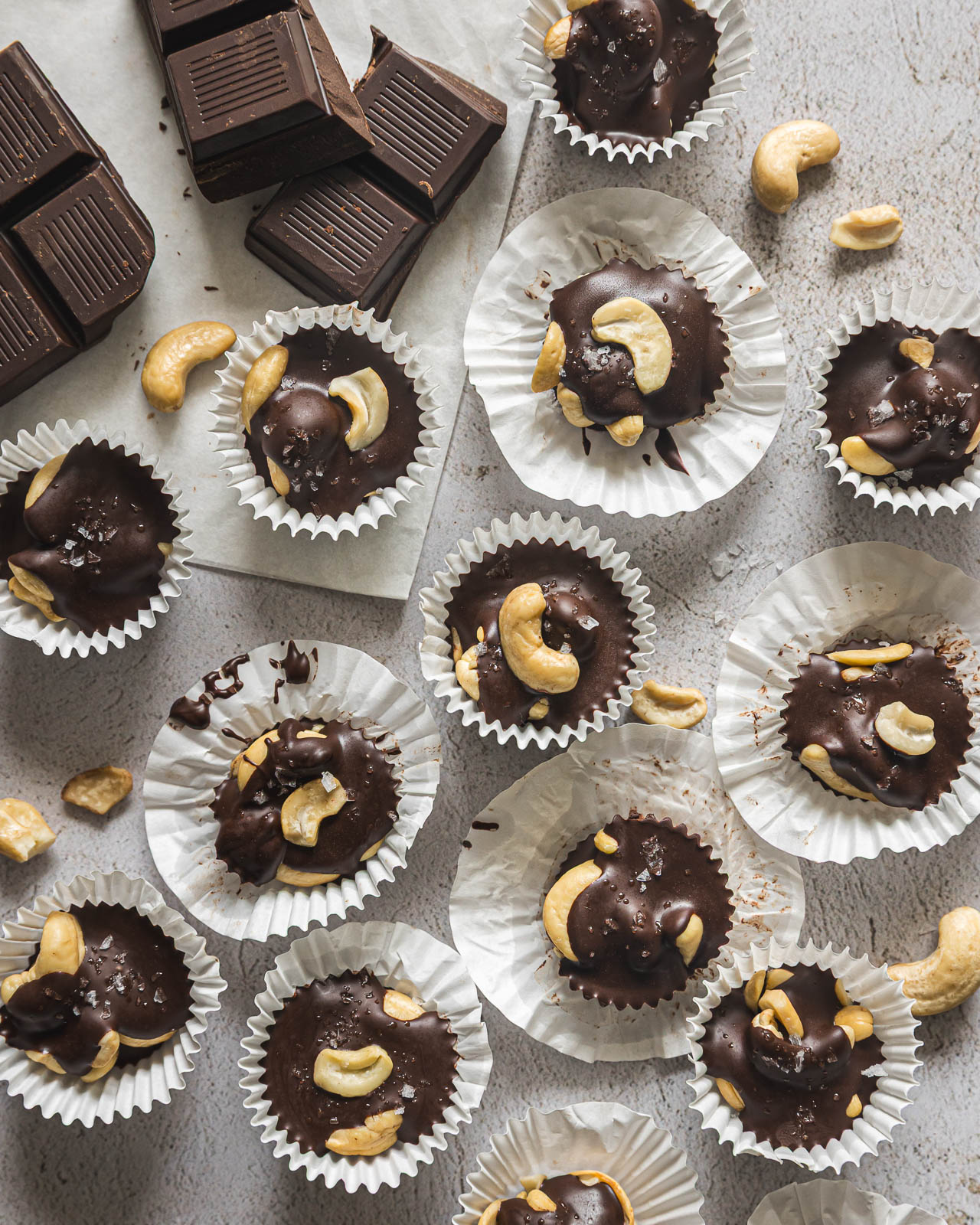 Chocolate covered cashew clusters in mini muffin liners with dark chocolate and sea salt