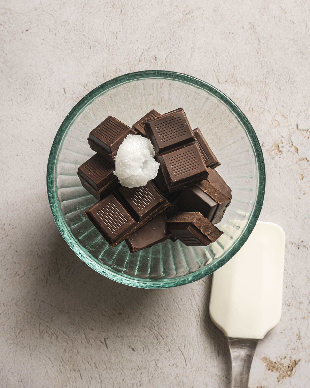 Chopped dark chocolate and coconut oil in a glass bowl before melting