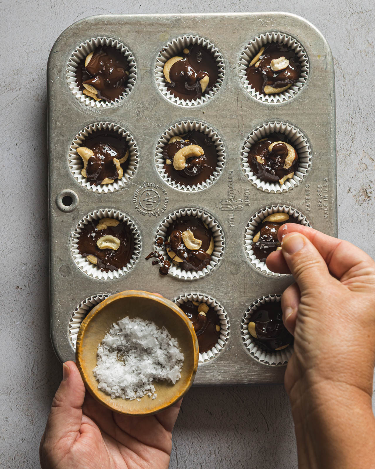Sprinkling flaky sea salt over dark chocolate cashew clusters before chilling