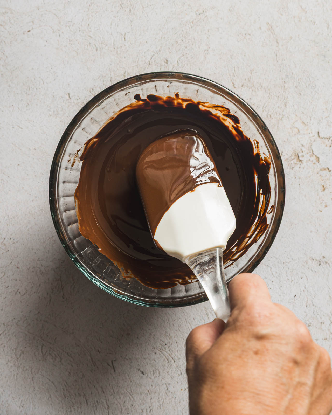 Stirring melted dark chocolate and coconut oil until smooth