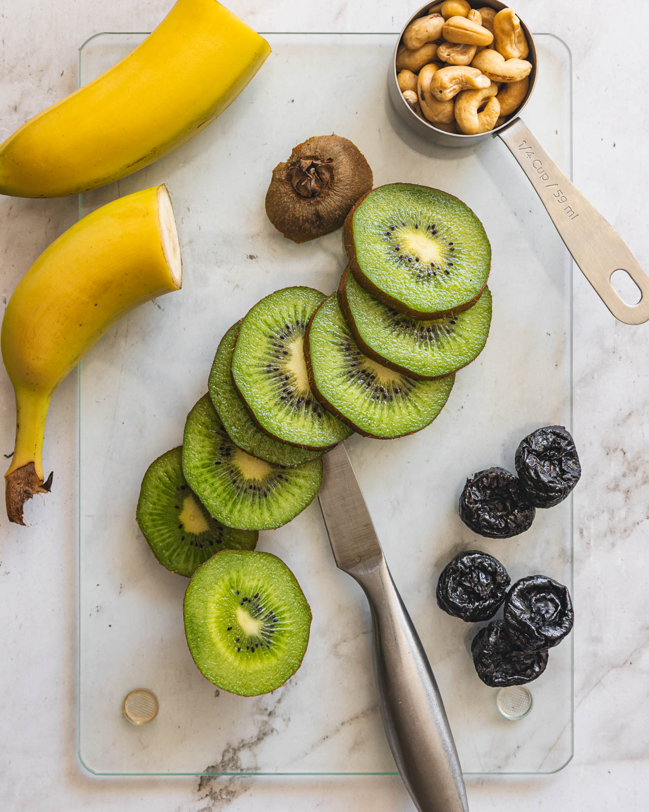 Kiwi, banana, prunes and cashews arranged for a healthy snack plate