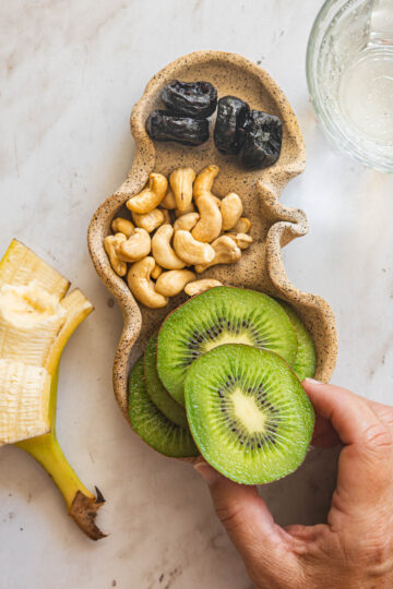 Kiwi banana cashew snack plate with fruit, prunes and cashews