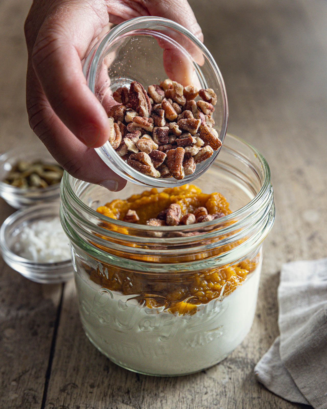 Adding chopped pecans to a pumpkin Greek yogurt bowl
