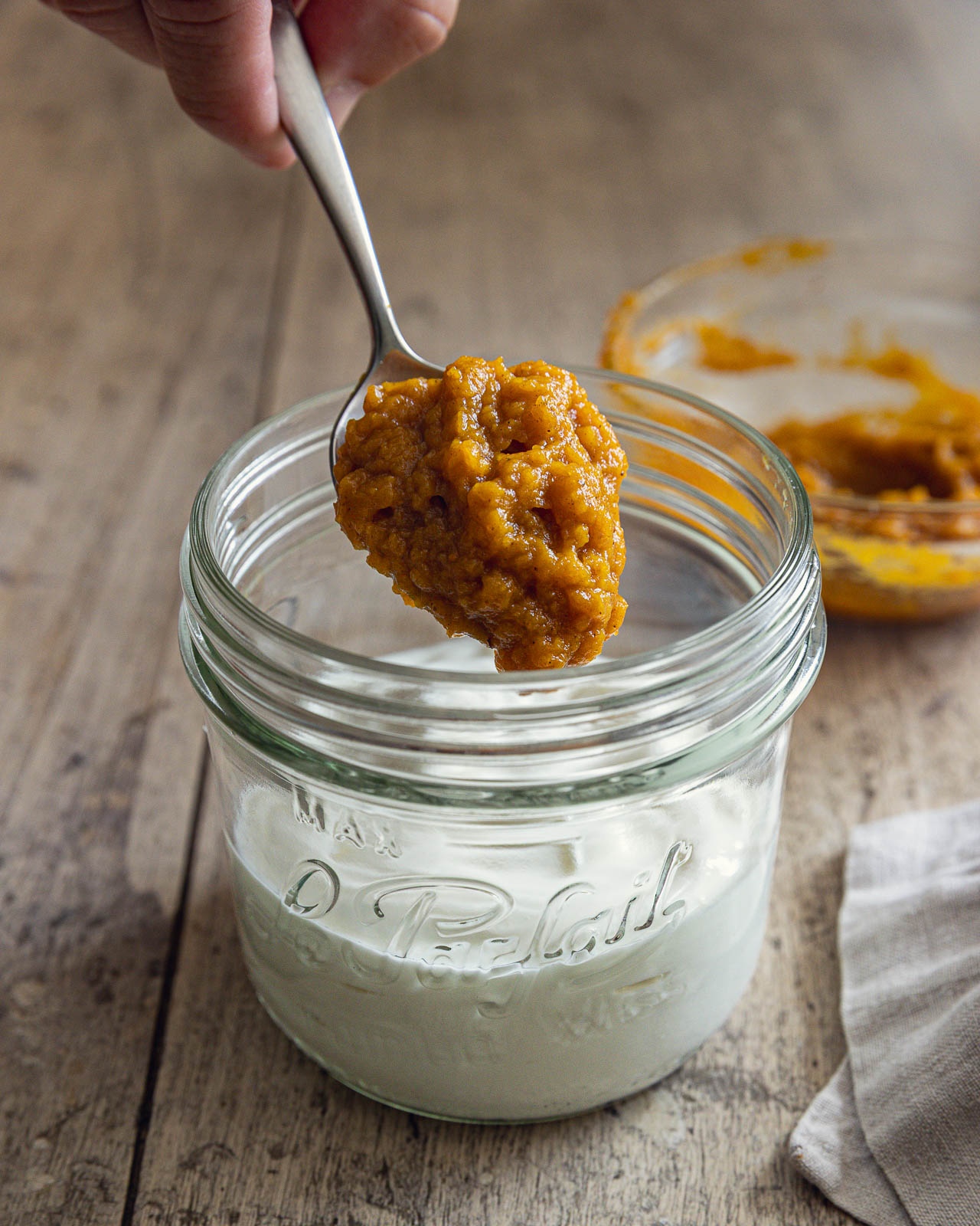Spooning spiced pumpkin purée over plain Greek yogurt