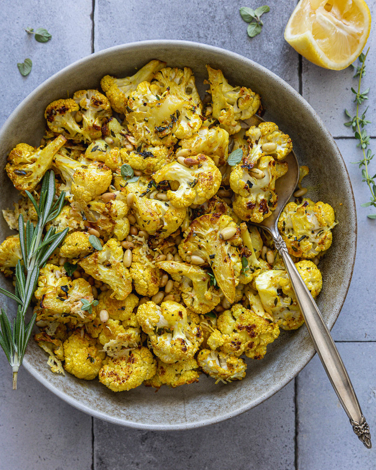 Golden roasted cauliflower with pine nuts, Parmesan, rosemary, thyme and oregano in a serving bowl