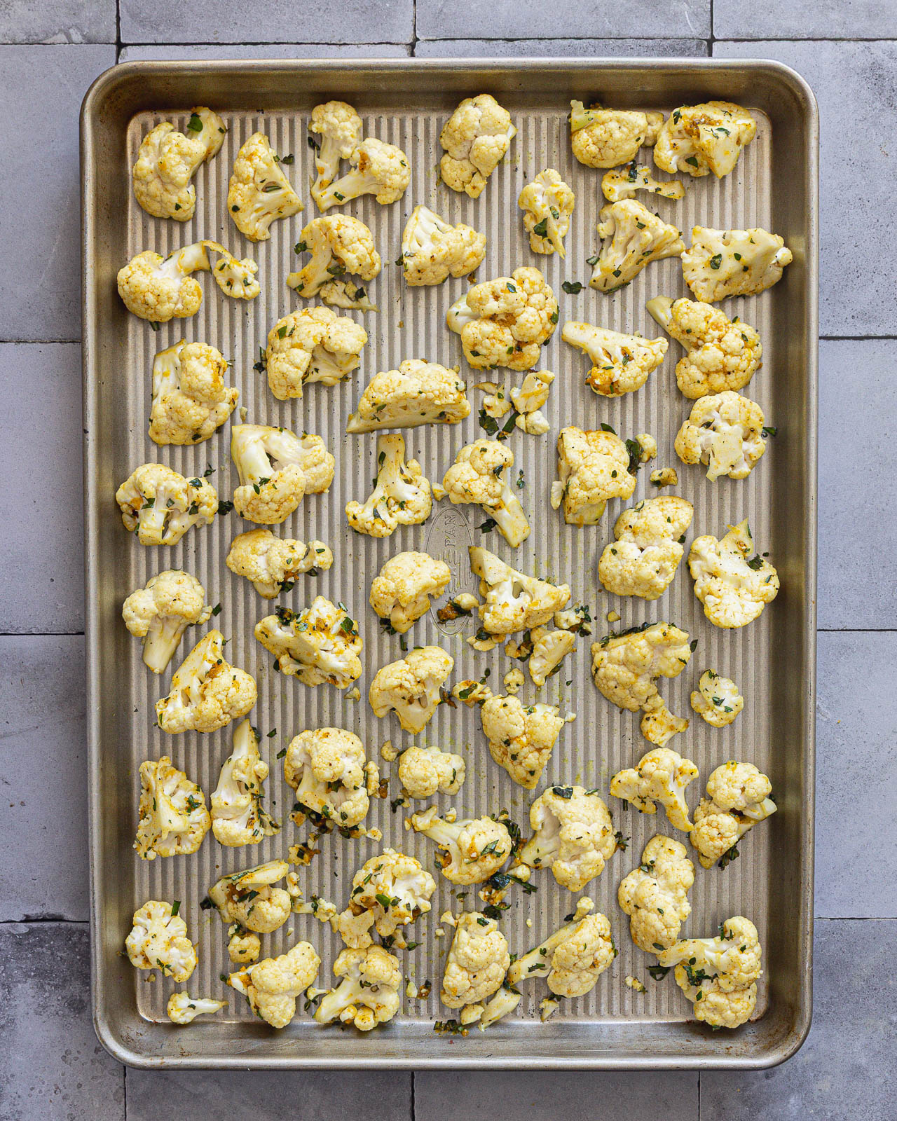Seasoned cauliflower florets arranged in a single layer on a metal sheet pan