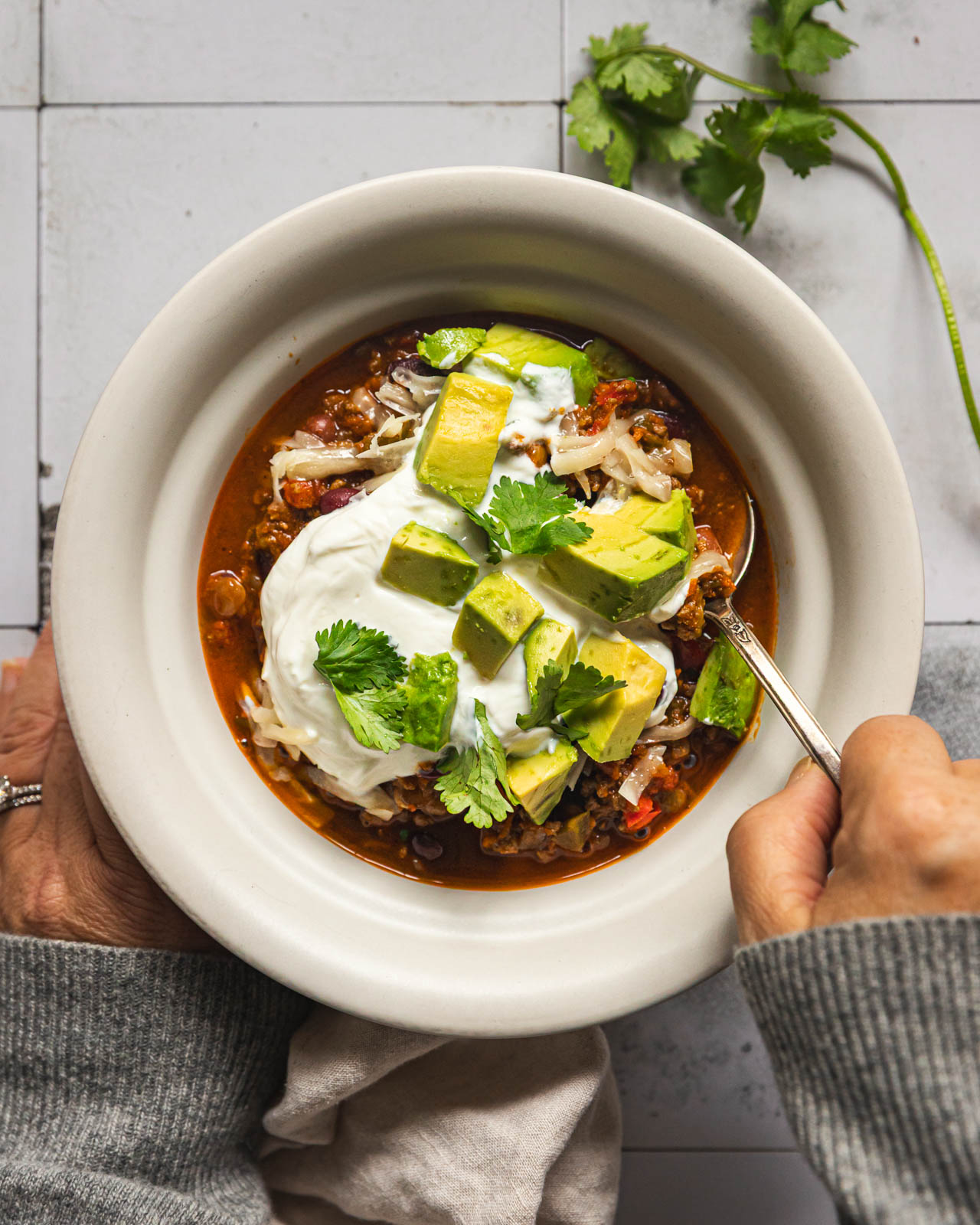 Bowl of smoky beef lentil chili topped with Greek yogurt, avocado and cilantro