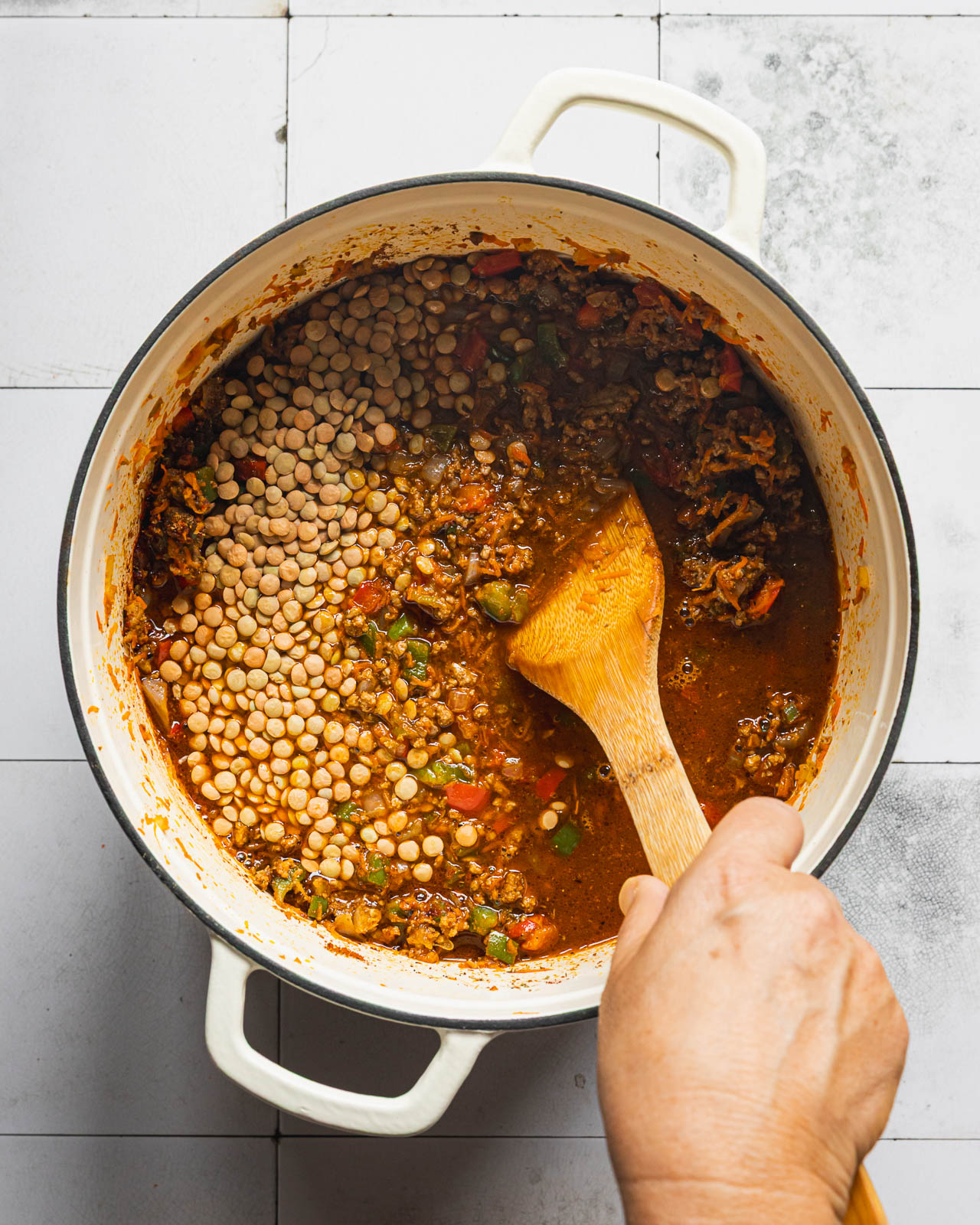 Brown lentils simmering with ground beef and vegetables in a Dutch oven