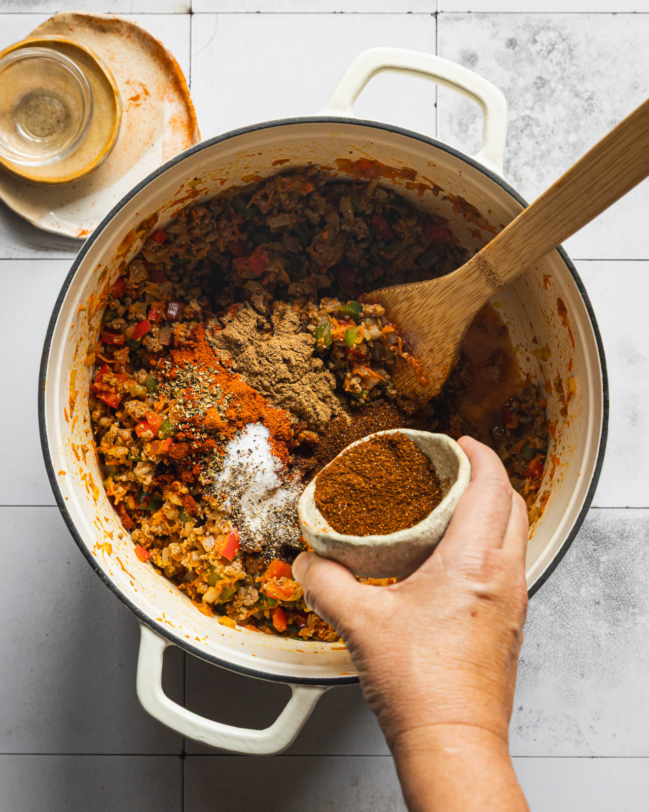 Adding spices to ground beef and vegetables for chili