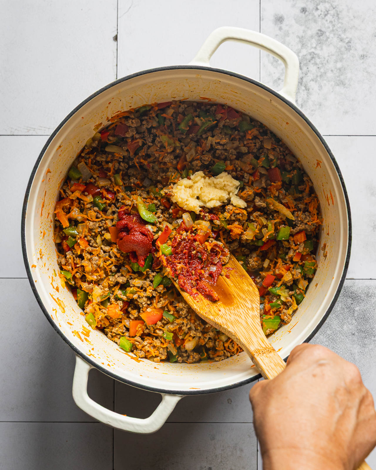 Ground beef and vegetables cooking with tomato paste and minced garlic in a Dutch oven