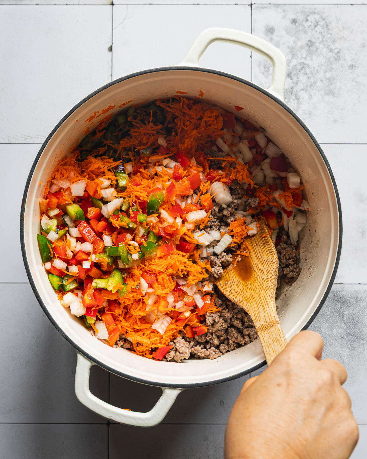 Diced peppers, onion and grated carrots cooking with ground beef