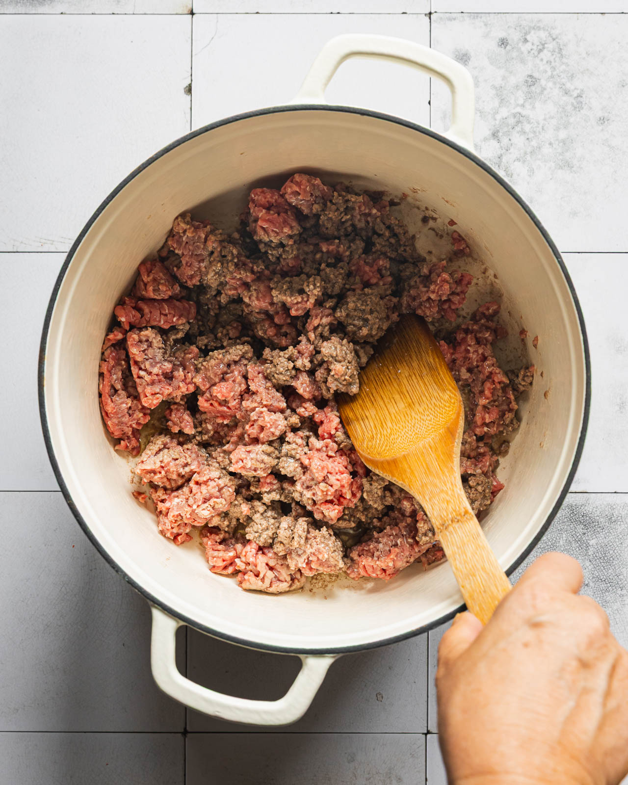 Browning lean ground beef in a white Dutch oven