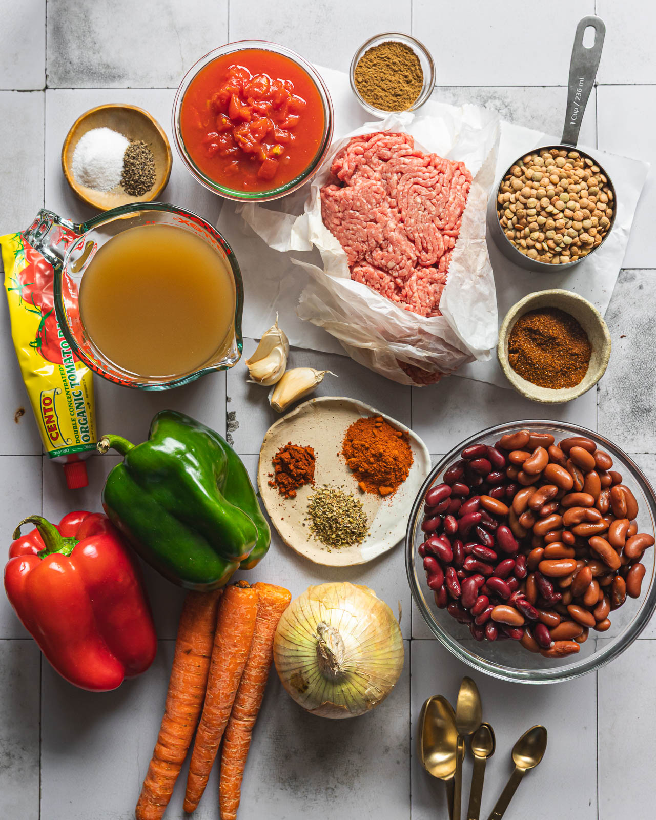 Ingredients for smoky beef lentil chili arranged on a white surface