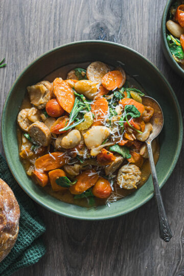 Bowl of butter bean stew with Italian chicken sausage, carrots, tomatoes and kale