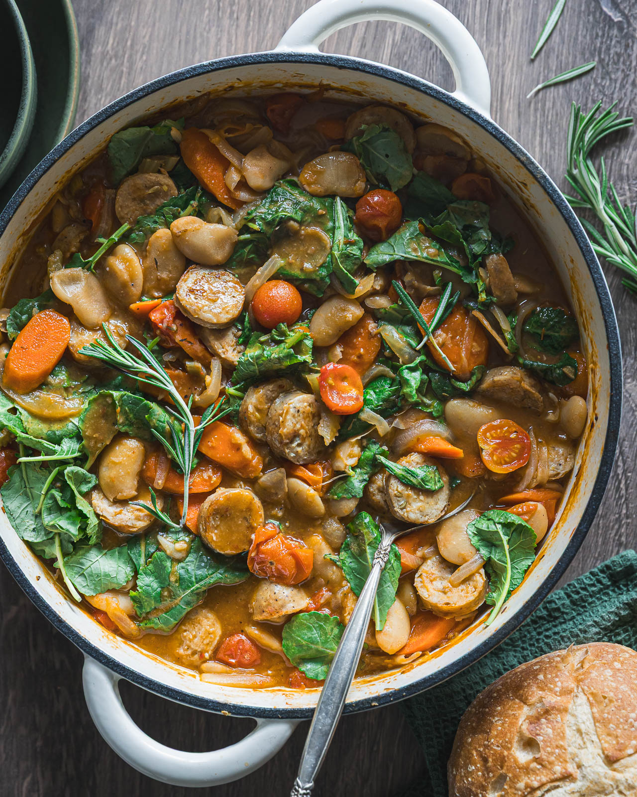 Braiser filled with butter bean stew, sliced chicken sausage, carrots, tomatoes and kale
