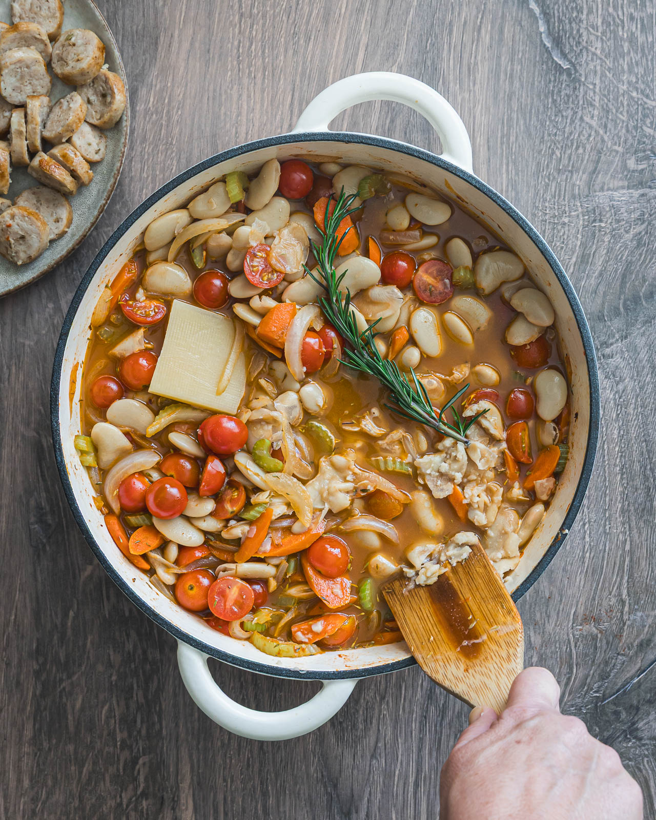 Butter beans, carrots and tomatoes simmering in broth in a braiser