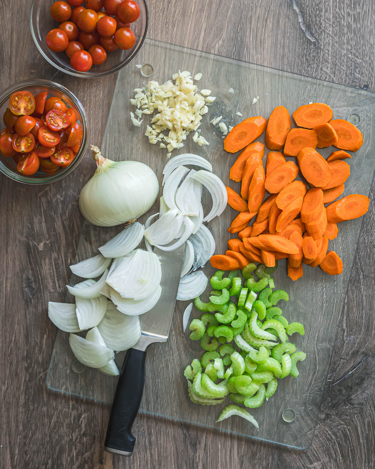 Sliced onion, carrots and celery prepared on a cutting board