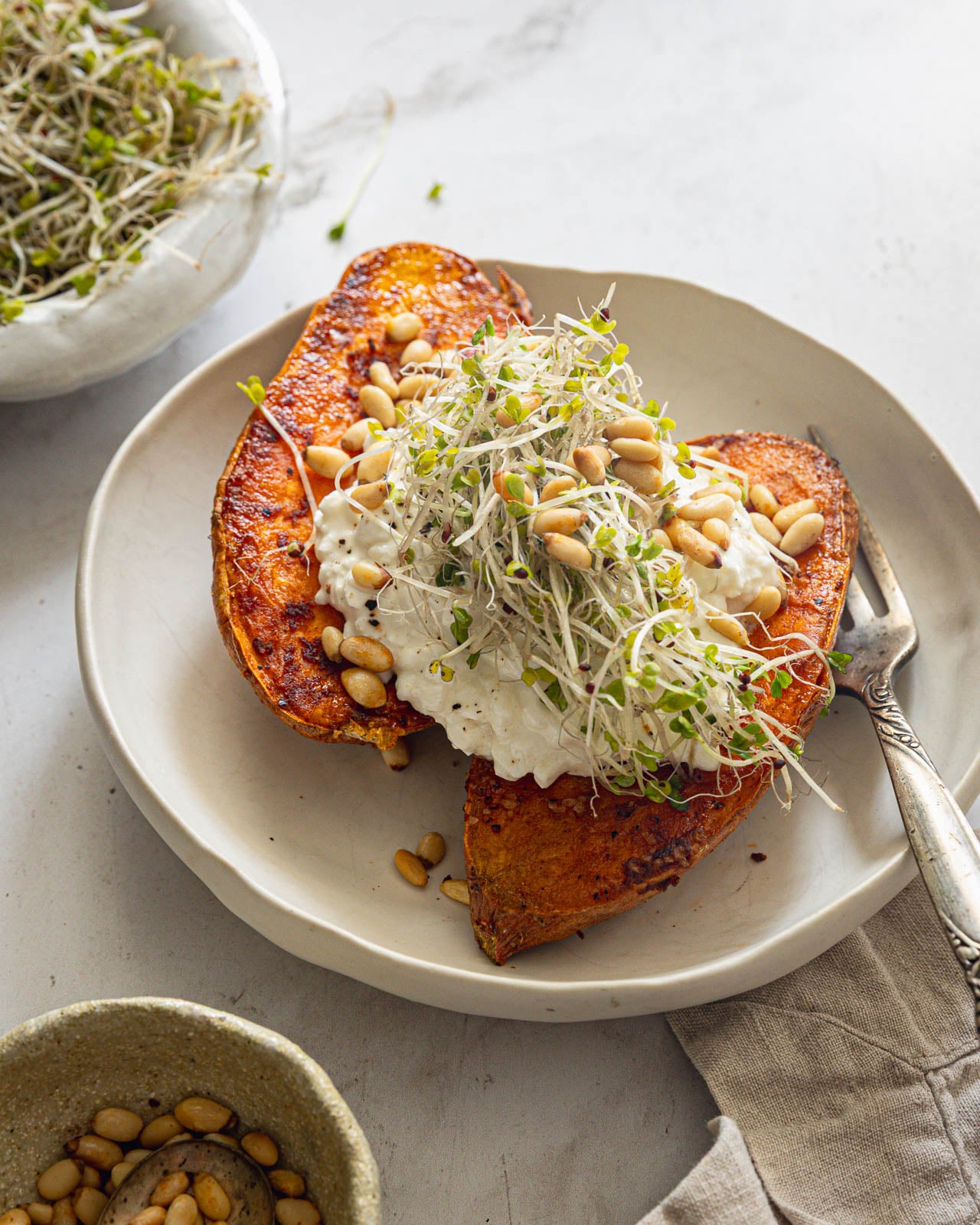 Close-up of caramelized sweet potatoes with cottage cheese, pine nuts and microgreens