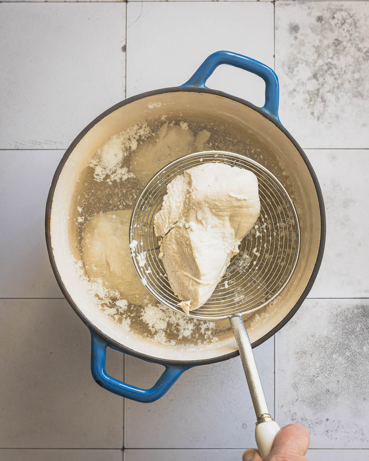 Chicken breasts poaching in a pot of water