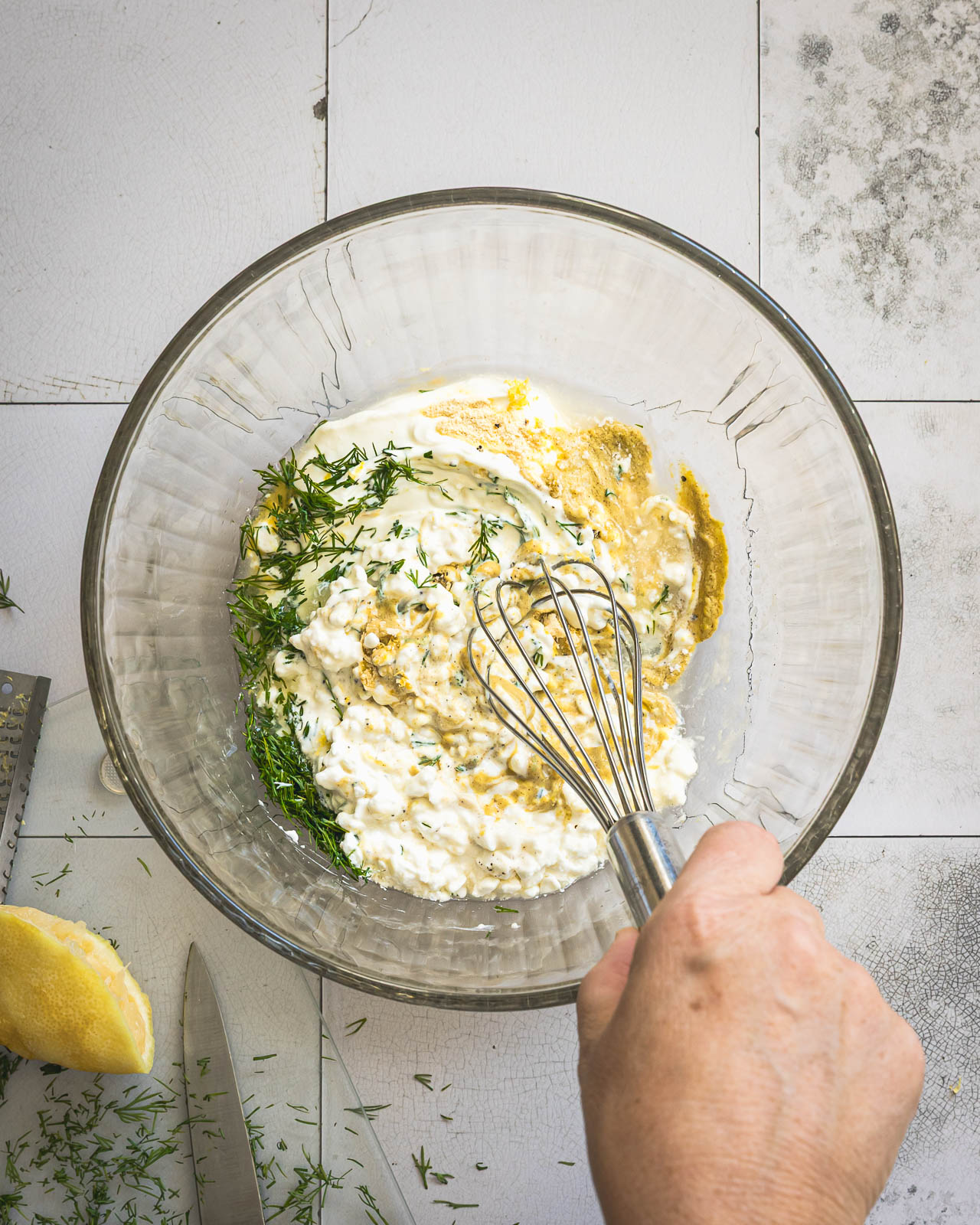 Whisking Greek yogurt and cottage cheese dressing with fresh dill