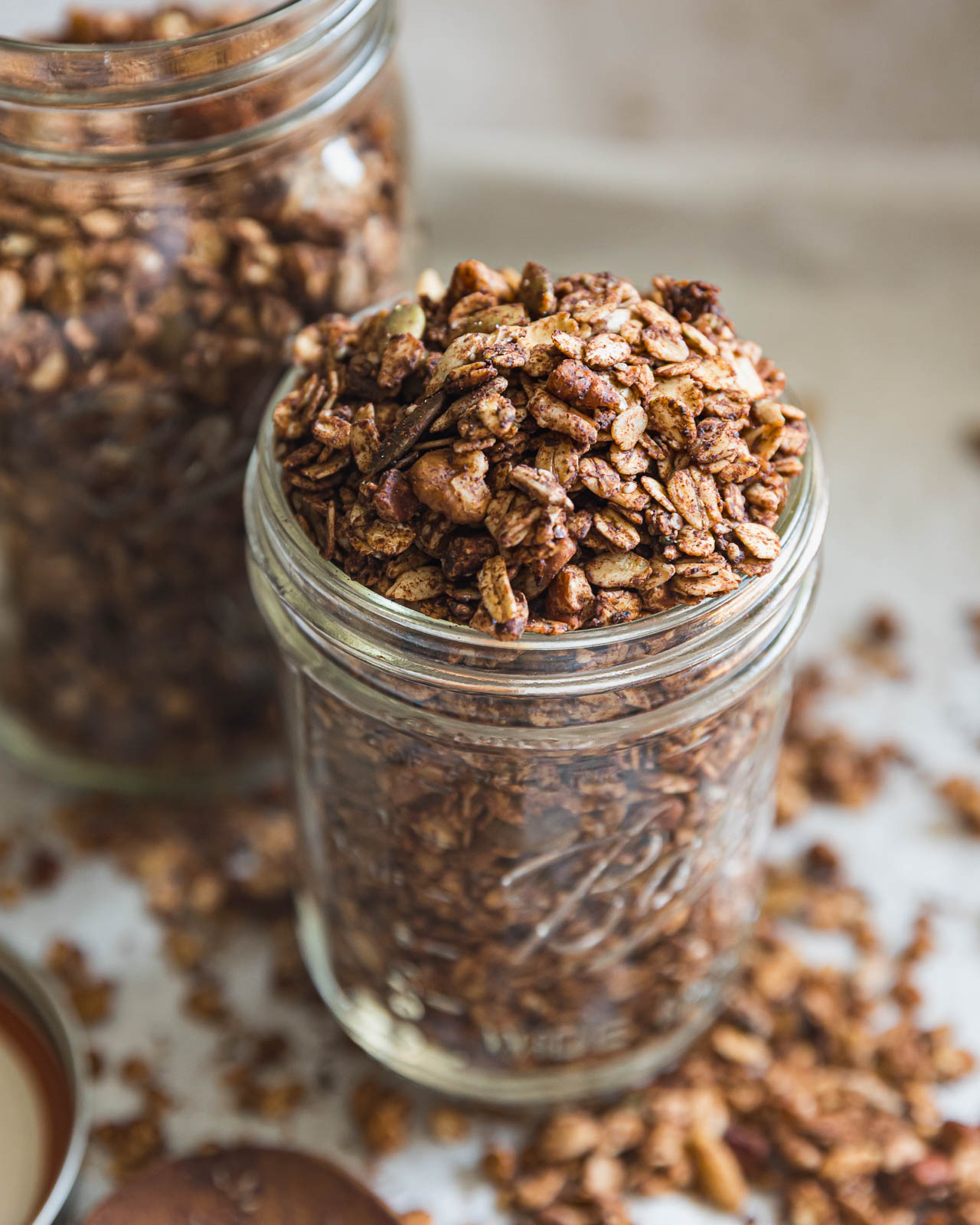 Chocolate granola with cacao, nuts and seeds overflowing from a glass mason jar