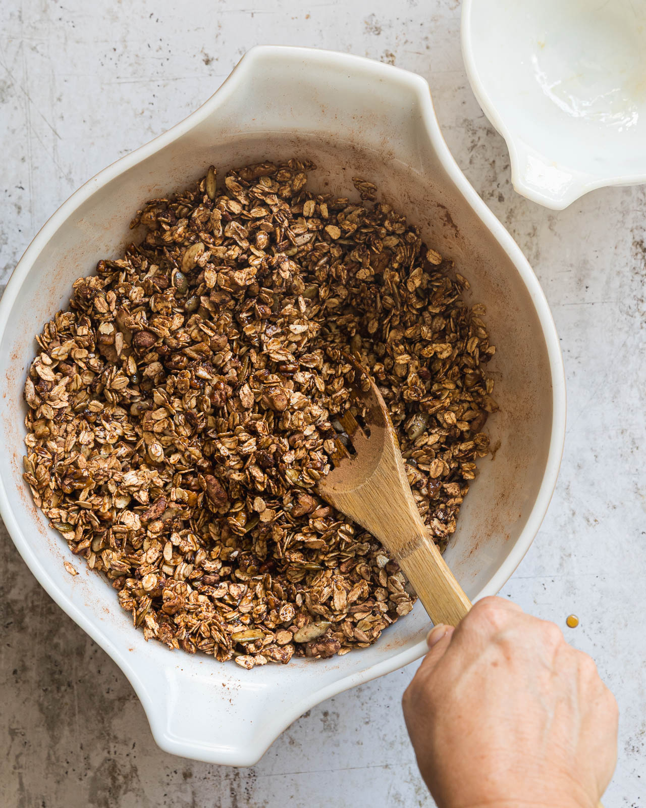 Wet and dry ingredients being combined in a large bowl to make homemade chocolate granola